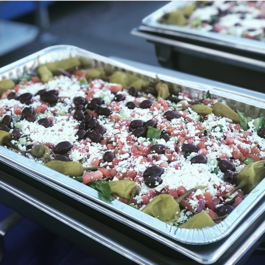 Mediterranean salad in a catering tray with olives, tomatoes, cucumbers and feta cheese crumbles